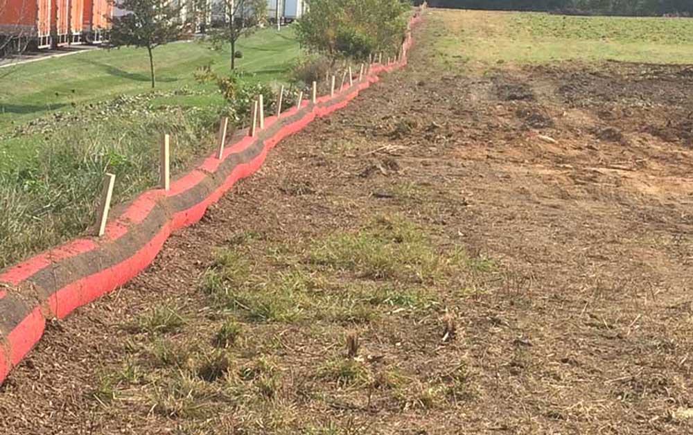 Specialty Products 2 plot of land with red and black barrier with wooden stakes, dirt
